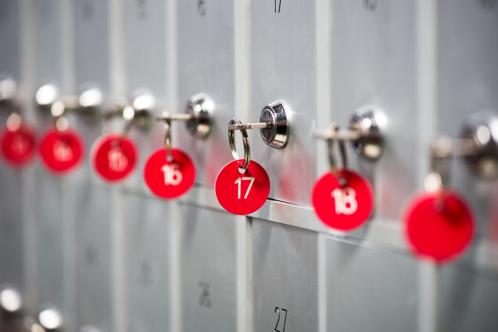 Row of metal lockers with locks, keys and numbered red tags in a sports changing room